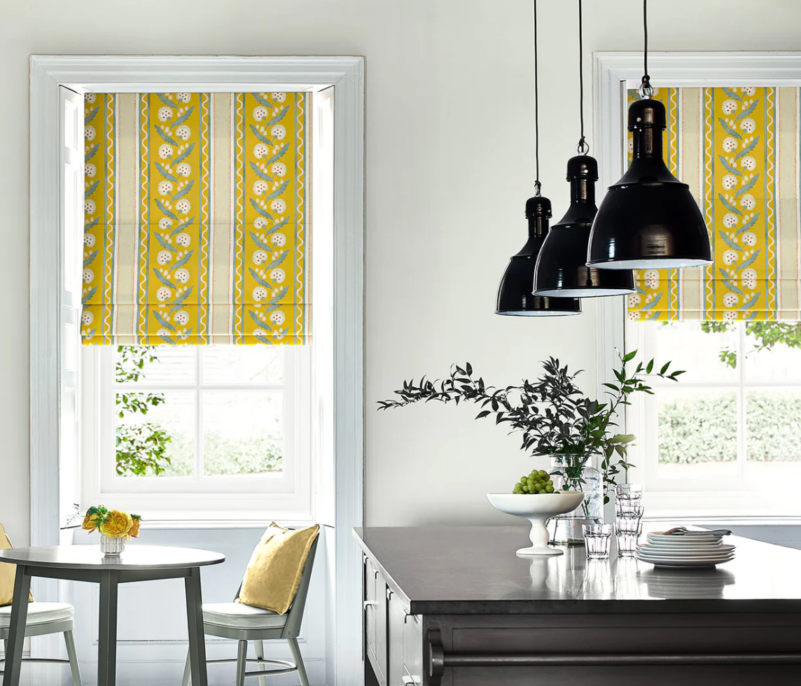 Modern kitchen with yellow patterned roman blinds, black pendant lights, and a dining table. linen linwood